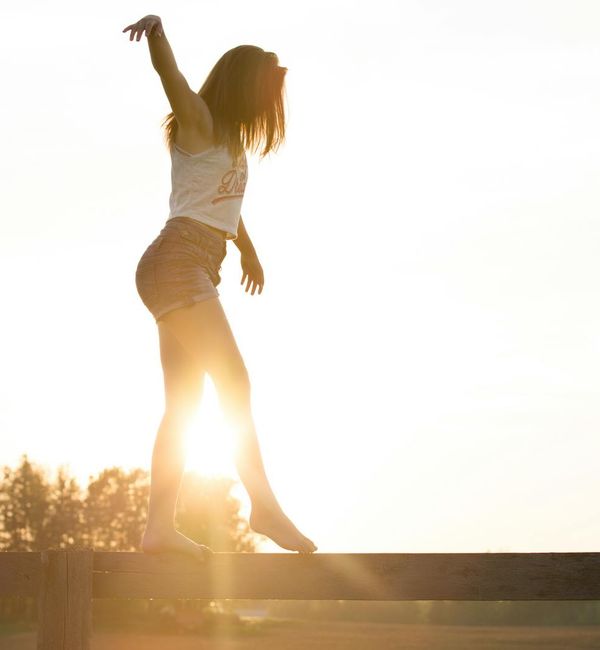 Silhouette of a person in a powerful yoga stance against a sunrise.