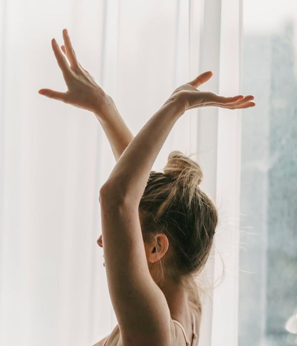 Woman in a graceful and gentle yoga pose in a dark, calm environment.
